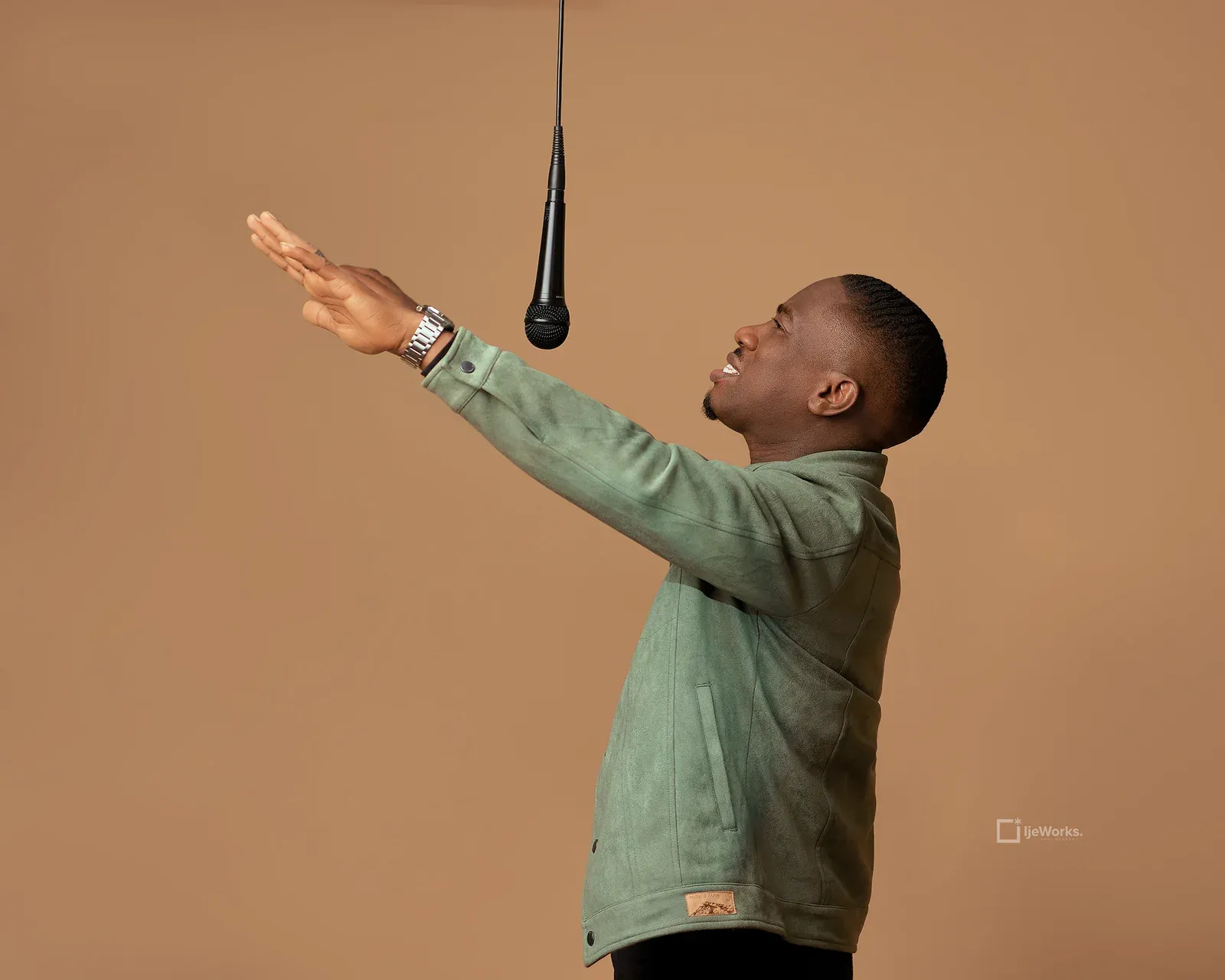 David Nkennor reaching upward toward a suspended microphone.